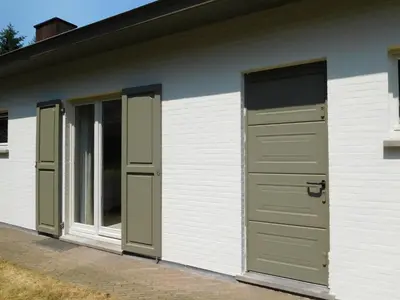 a white building with green doors and windows at Suite Horatio in Heusden - Zolder
