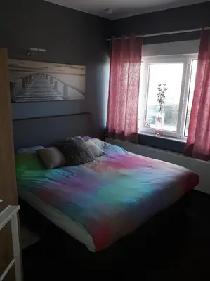 a bed with a colorful blanket in a room with a window at Villa Marco 176 in Cerexhe-Heuseux