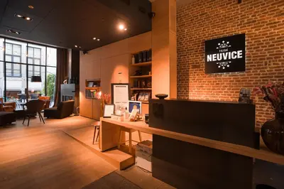 a lobby with a newsagency sign on a brick wall at Hotel Neuvice in Liège