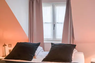 a bed with two pillows in front of a window at Hotel Neuvice in Liège