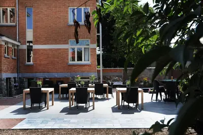 a patio with tables and chairs in front of a building at Charmehotel Villa Saporis in Hasselt