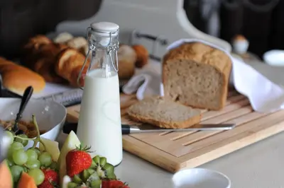 a loaf of bread on a cutting board with a bottle of milk at Charmehotel Villa Saporis in Hasselt