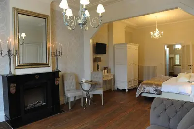 a bedroom with a bed and a fireplace and a mirror at Charmehotel Villa Saporis in Hasselt