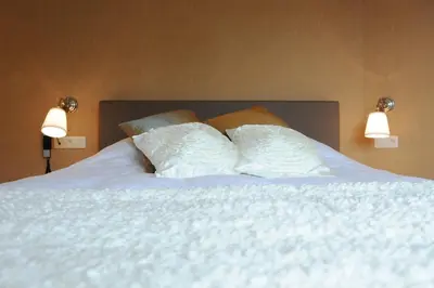 a bed with white sheets and pillows on it at Charmehotel Villa Saporis in Hasselt