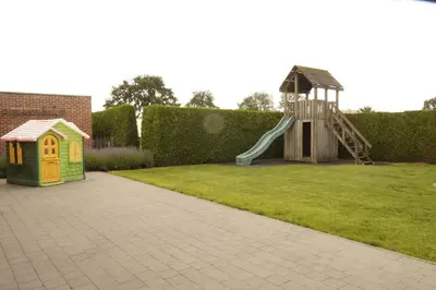 a playground with a slide and a play house at Kampenhof in Maaseik