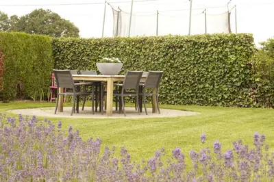 a table and chairs in a garden with purple flowers at Kampenhof in Maaseik