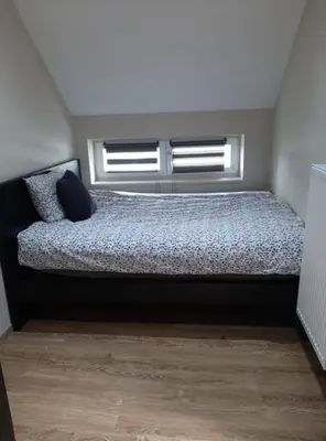 a bed in a room with two windows at Chez Vivi in Ans
