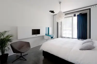 a bedroom with a bed and a chair and a tv at B&B Bed and Beyond in Oudsbergen