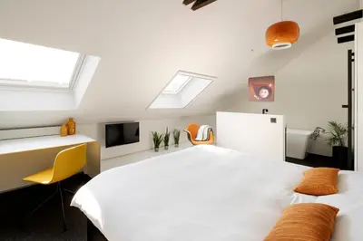 a bedroom with a white bed and a desk and a tv at B&B Bed and Beyond in Oudsbergen
