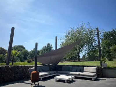 a couch and a table with an umbrella at B&B Bed and Beyond in Oudsbergen