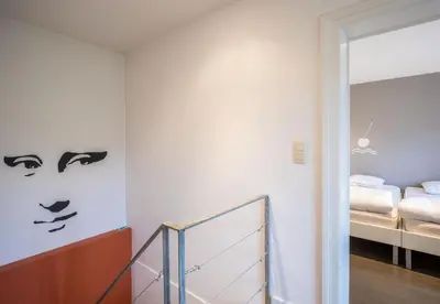 a bedroom with a hallway with two beds in the background at De Waterkriek in Borgloon