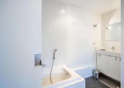 a white bathroom with a tub and a sink at De Waterkriek in Borgloon