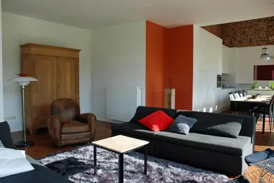 a living room with a black couch and a chair at De Waterkriek in Borgloon
