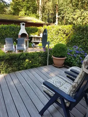a deck with a rocking chair and a grill at Charme chalet in Zutendaal