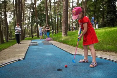 a little girl playing golf on a miniature golf course at Charme chalet in Zutendaal