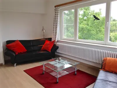 a living room with a black couch and a glass table at De tuin van Agatha in Kortessem