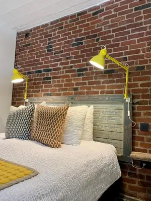 a bed with two lights on a brick wall at Vakantiehuis ABEL in Dilsen-Stokkem