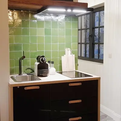 a kitchen with a sink and a green tiled wall at Vakantiehuis ABEL in Dilsen-Stokkem