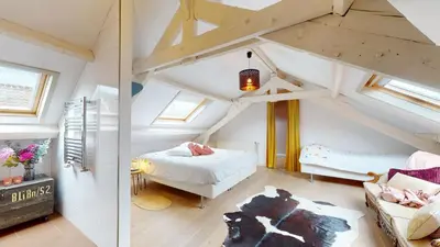 a attic room with a bed and a couch at SintPieter17 Lo-Ghis vakantiewoning in Voeren