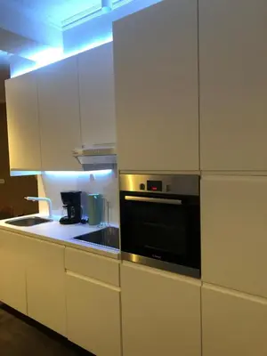 a kitchen with white cabinets and a black oven at Domus Basil in Tongeren