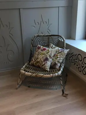 a wicker chair with two pillows on it in a room at Domus Basil in Tongeren