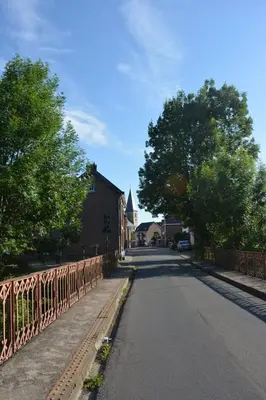 an empty street with a fence and a church at Vakantiewoning Bij de Jep in Bilzen