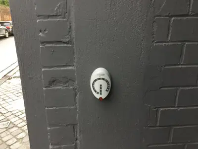 a white object on a black brick wall at L’atelier St Remacle in Liège