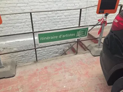 a green street sign on a rail next to a building at L’atelier St Remacle in Liège