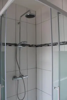 a shower in a bathroom with white tiles at Logie Rotem in Dilsen-Stokkem