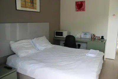 a bedroom with a bed and a desk with a microwave at Logie Rotem in Dilsen-Stokkem