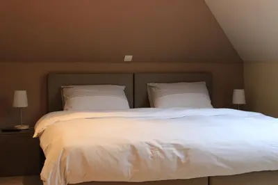 a bedroom with a large bed with white sheets and pillows at B&B Don Genaro in Dilsen-Stokkem