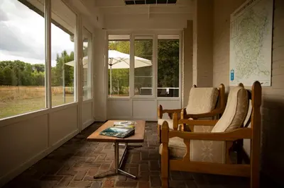 a room with chairs and a table and windows at Vakantiewoning Heidebos in het Nationaal Park Hoge Kempen in Het Laar