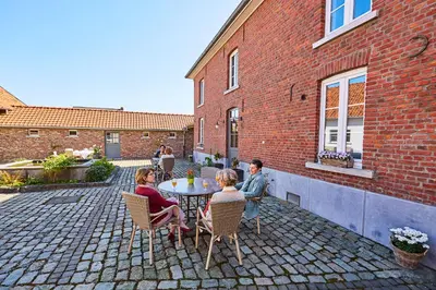 a group of people sitting around a table on a patio at Wellness B&B De Zevenslaper in Geetbets