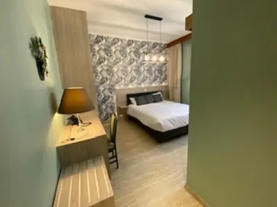 a bedroom with a bed and a desk with a lamp at Hotel IL Castellino in Chaudfontaine
