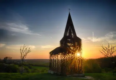 a tall building with the sun setting behind it at 'Hof der Heerlijckheid' in Borgloon