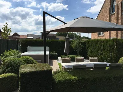 a patio with an umbrella and chairs and a pool at Le fond d'Or in Borgloon