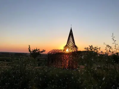 a church with the sunset in the background at Le fond d'Or in Borgloon