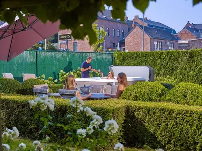 a group of people sitting around a table in a garden at Le fond d'Or in Borgloon