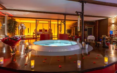 a jacuzzi tub in a living room with candles at Le Baiser de Shogun in Ensival