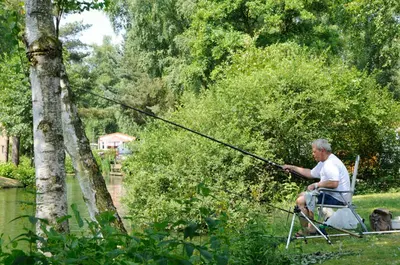 a man sitting in a chair holding a fishing pole at Vakantiewoning Zavelbos in Maaseik