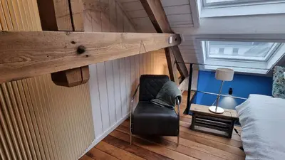 a black chair in a room with a bed at Een vleugje wellness in de Voerstreek - Bed & Brocante Onder de Poort in Voeren