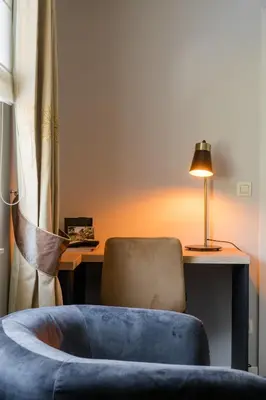 a room with a chair and a desk with a lamp at B&B De Floreffe in Overpelt
