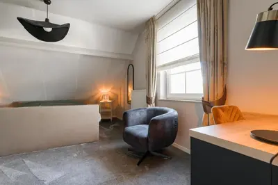 a room with a chair and a desk and a bed at B&B De Floreffe in Overpelt