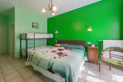 a bedroom with green walls and a bed and a chair at B&B Casa Roman & Vakantiewoning voor 1 pers tot max 32 personen in Zonhoven