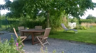 a wooden table and chairs in a garden at De Notelaar in Kortessem