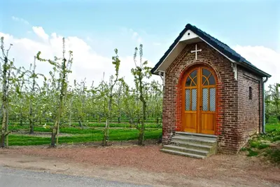 a small brick chapel with a wooden door in a vineyard at De Notelaar in Kortessem