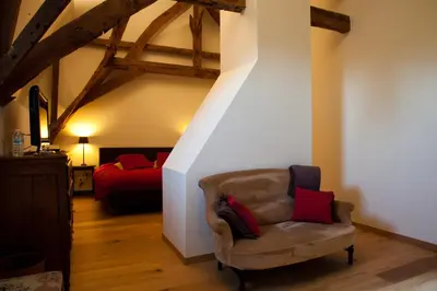 a living room with a chair and a bed at B&B Het Agnetenklooster in Maaseik