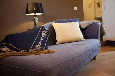 a blue couch with a pillow and a lamp at B&B Het Agnetenklooster in Maaseik