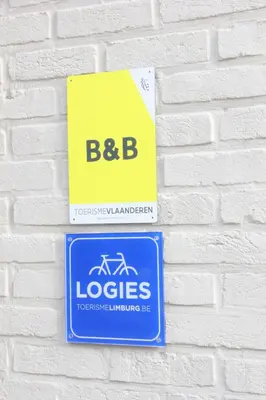 a sign on a white brick wall at AMADIS in Kesselt