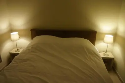 a bedroom with a bed with two lamps on it at Holiday home La ferme brabant in Voeren